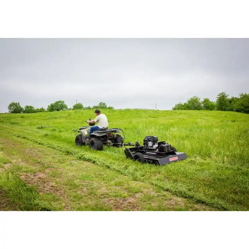 Operator on ATV pulling Swisher 44-inch rough cut mower with 14.5HP engine across grassy field, gallery position 1