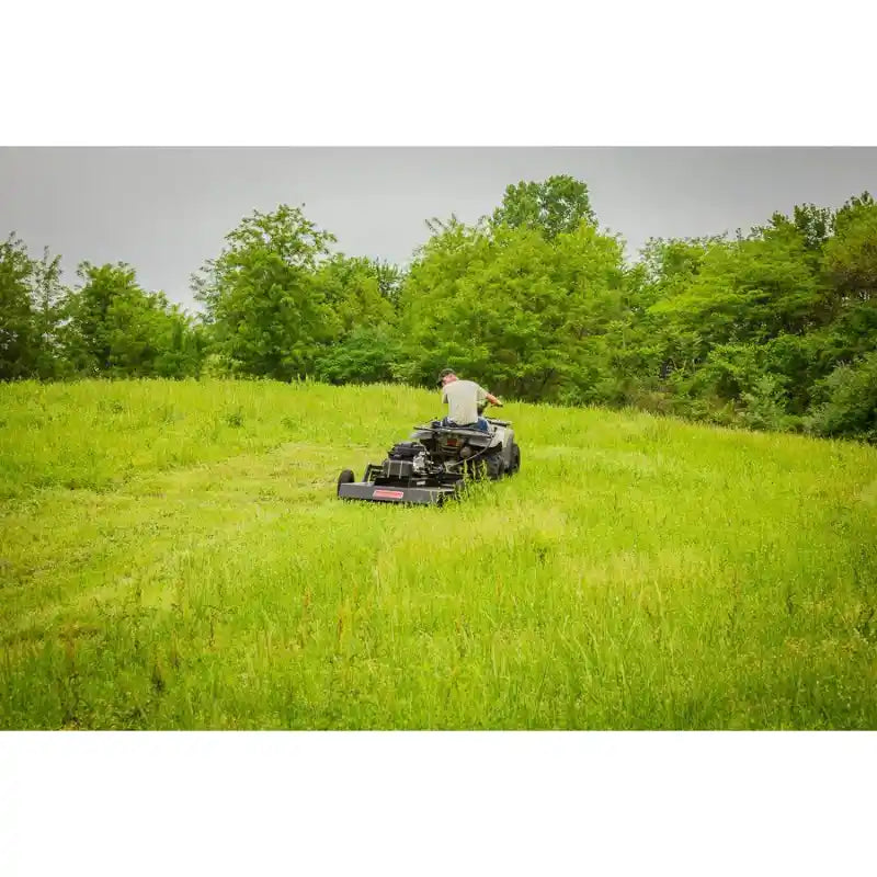 Operator on ATV towing Swisher 44-inch rough cut mower across tall grass, image from product gallery position 1