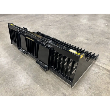 Black steel skid steer rock bucket attachment with reinforced vertical tines and curved teeth on smooth concrete floor