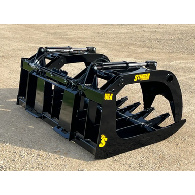 Black steel root grapple skid steer attachment with dual hydraulic cylinders and reinforced curved tines on gravel surface