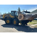 Yellow Komatsu WA270 loader with grapple attachment lifting large tree log on residential street under clear sky