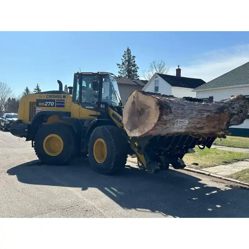 Yellow Komatsu WA270 loader with grapple attachment lifting large tree log on residential street under clear sky