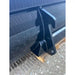 Close-up of black steel skid steer bucket attachment showing welds and reinforced mounting hook on gravel surface