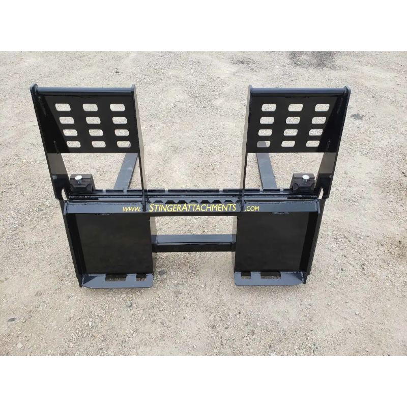 Black painted steel pallet fork attachment with reinforced backrest plates and dual fork tines on dirt surface