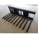 Skid steer attachment with nine long black metal tines and rectangular mounting frame on concrete floor indoors