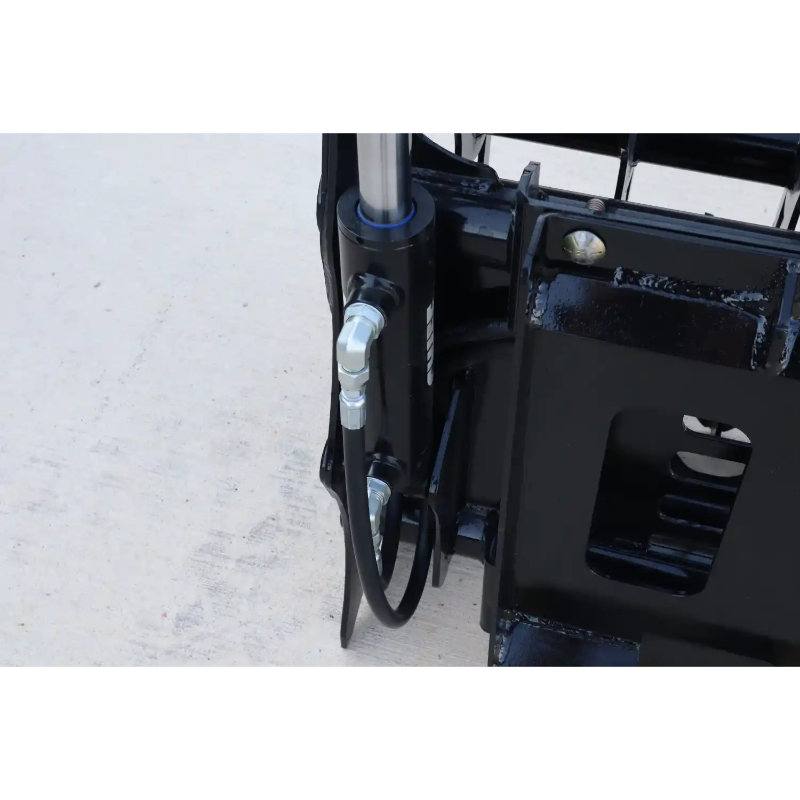 Close-up of black hydraulic cylinder and hoses connected to steel mounting bracket on concrete surface