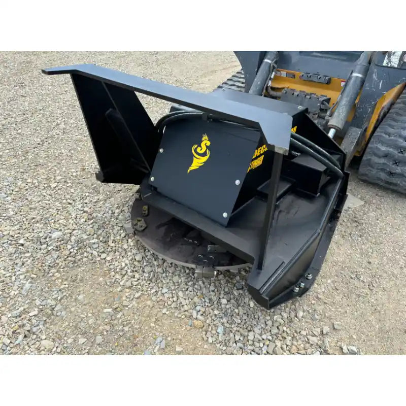 Black mulcher attachment with cutting teeth and protective steel housing mounted on skid steer loader on gravel