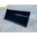 Clean black steel tractor loader bucket attachment resting on compacted gravel surface outdoors