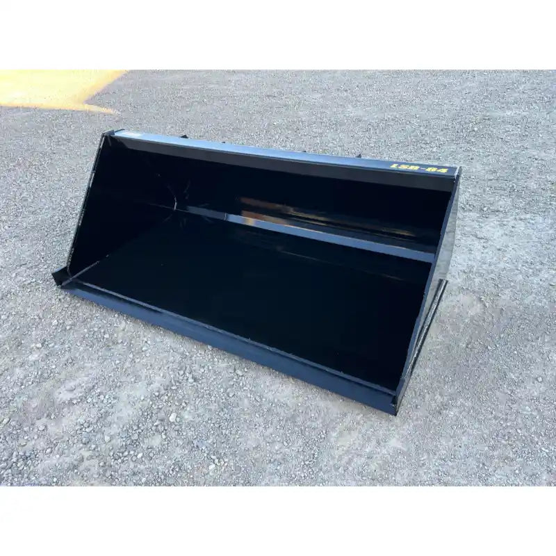 Clean black steel tractor loader bucket attachment resting on compacted gravel surface outdoors