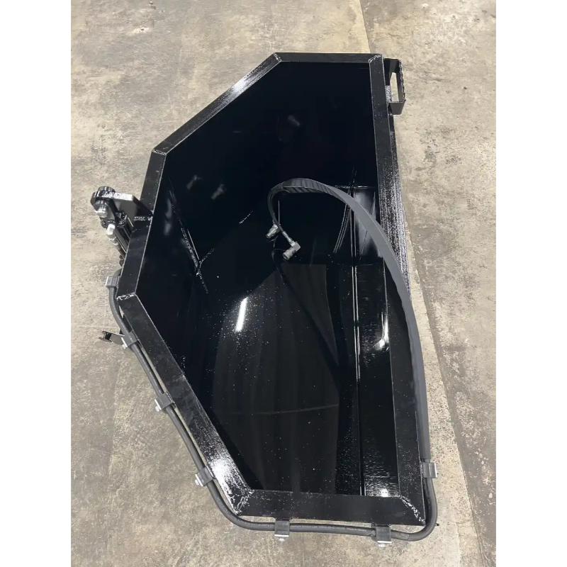 Black steel skid steer concrete bucket with smooth interior and rear mounting brackets on concrete floor