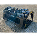 Black steel rock grapple attachment with hydraulic arms and wide spaced tines resting on gravel ground
