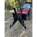 Black steel tractor-mounted tree puller attachment with serrated gripping arms and reinforced frame on grassy forest ground