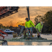 Three construction workers using MBW 501H ScreeDemon gas-powered vibratory wet screed to level concrete at sunset, gallery position 1