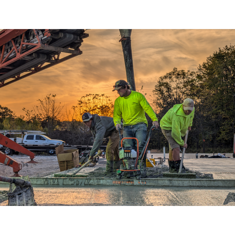 Three construction workers using MBW 501H ScreeDemon gas-powered vibratory wet screed to level concrete at sunset, gallery position 1