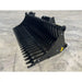 Black rock bucket skid steer attachment with spaced tines and reinforced side plates on concrete floor