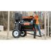 Tow-behind mortar mixer with black barrel, orange safety grate, MBW logo, and pneumatic tires on dirt construction site
