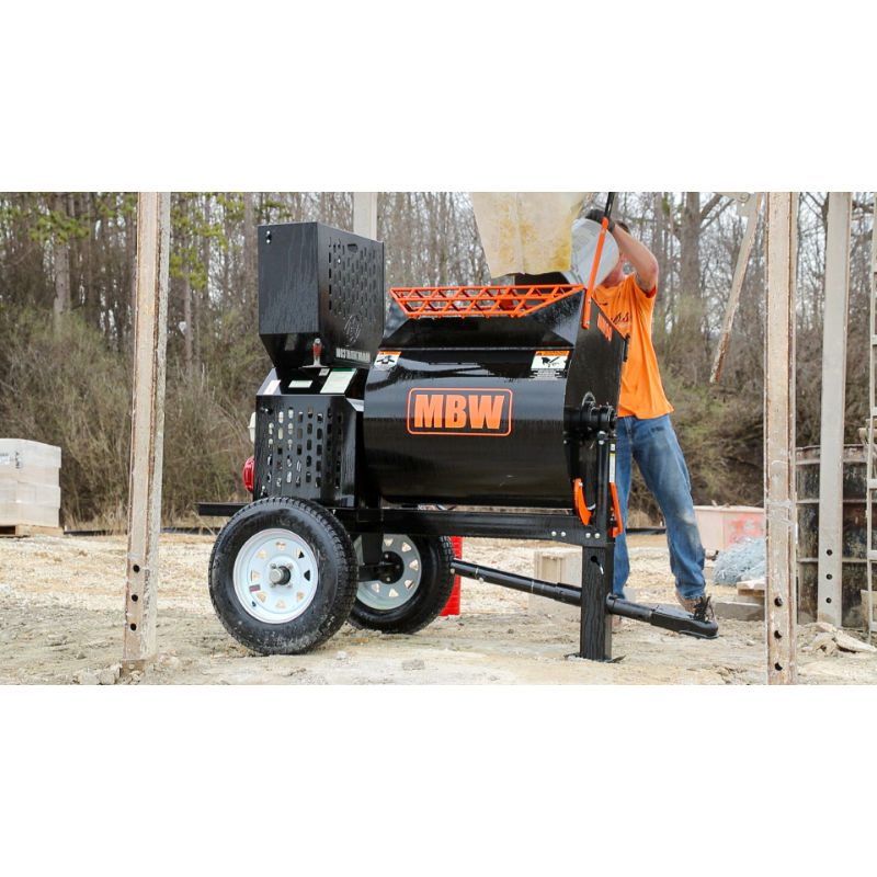 Tow-behind mortar mixer with black barrel, orange safety grate, MBW logo, and pneumatic tires on dirt construction site