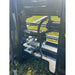 Close-up of hydraulic hose connections and metal fittings on black skid steer pallet fork attachment over grass field