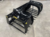Pair of black hydraulic grapple attachments with teeth, resting on concrete floor indoors