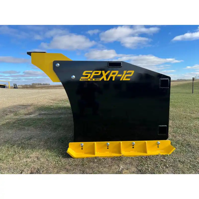 Side view of black and yellow steel snow pusher blade with bolt-on cutting edge resting on grass field