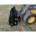 Black steel clam grapple attachment connected to skid steer loader with hydraulic hoses on grassy ground outdoors
