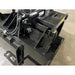 Black steel demolition grapple bucket attachment showing hydraulic cylinder, hoses, and reinforced welds on indoor concrete floor