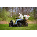 Operator riding ATV fitted with Swisher spreader dispersing material over grass from rear, gallery position 1