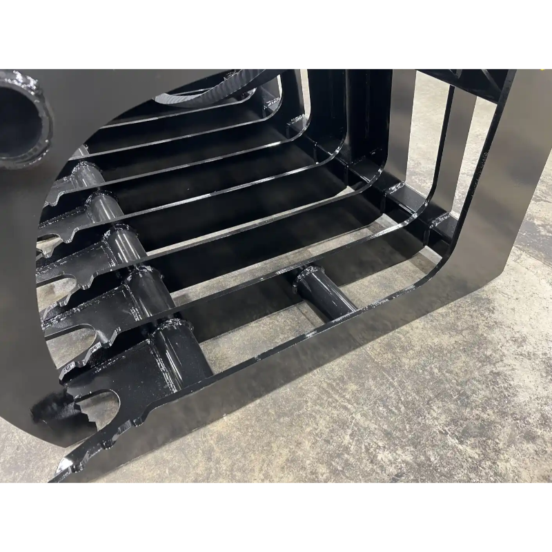 Black steel grapple attachment with spaced curved tines and reinforced welds on a concrete floor surface