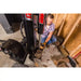 Operator positioning large log onto Swisher 22-Ton Timber Brute Eco Split electric log splitter in gallery position 1 indoors
