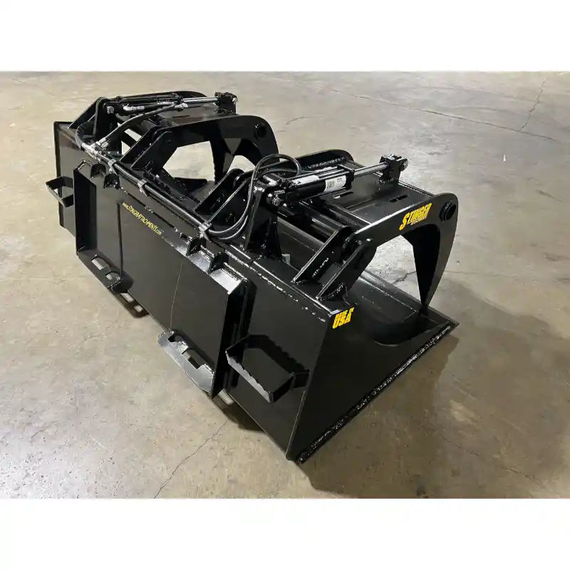 Black steel demolition grapple bucket attachment with dual hydraulic arms and clamp teeth on concrete floor indoors