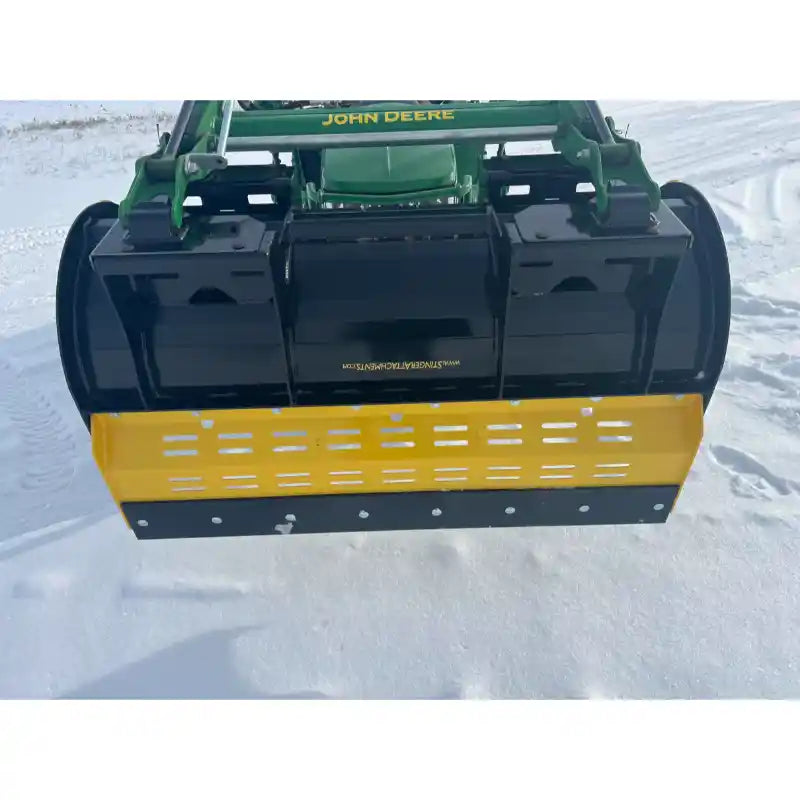 Yellow and black steel snow pusher attachment mounted on green John Deere skid steer loader over snow-covered ground