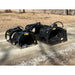 Three black metal rock grapple attachments with spaced tines and hydraulic hoses arranged on gravel driveway outdoors
