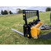 Black steel skid steer pallet fork attachment with perforated backrest and two flat fork tines on grass field