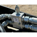 Metal hydraulic coupler block with four connected steel hydraulic hoses and fittings on black equipment frame