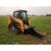 Yellow tracked compact skid steer loader with enclosed cab and black stump bucket attachment on grass field