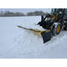 Yellow skid steer with black snow pusher attachment clearing snow on a snow-covered open field outdoors