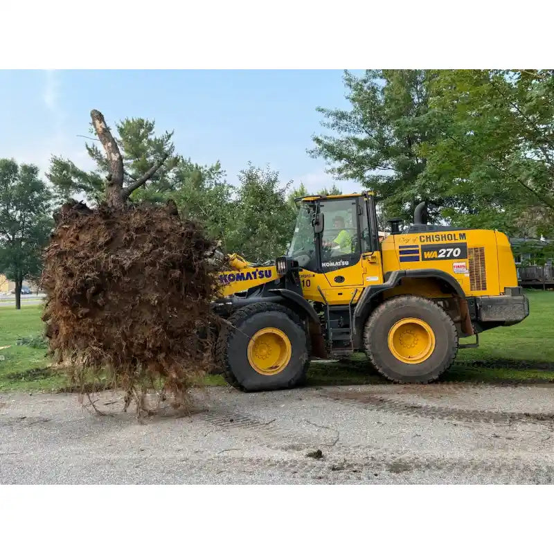 Yellow Komatsu WA270 loader lifting large tree root ball on grassy and gravel surface near trees