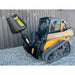 Yellow John Deere compact track loader with black Stinger concrete mixer attachment on gravel surface near metal building wall