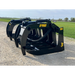 Black steel skid steer root grapple attachment with hydraulic cylinders, hydraulic hose, and visible mounting points on gravel road