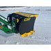 Compact black and yellow snow pusher attachment mounted on green skid steer loader arm in snowy field