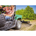 Operator in plaid shirt driving green utility vehicle towing Swisher 48" Driveway Grader on dirt surface, gallery position 1