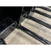 Close-up angled view of black welded steel tines attached to a skid steer manure spear bucket on concrete floor