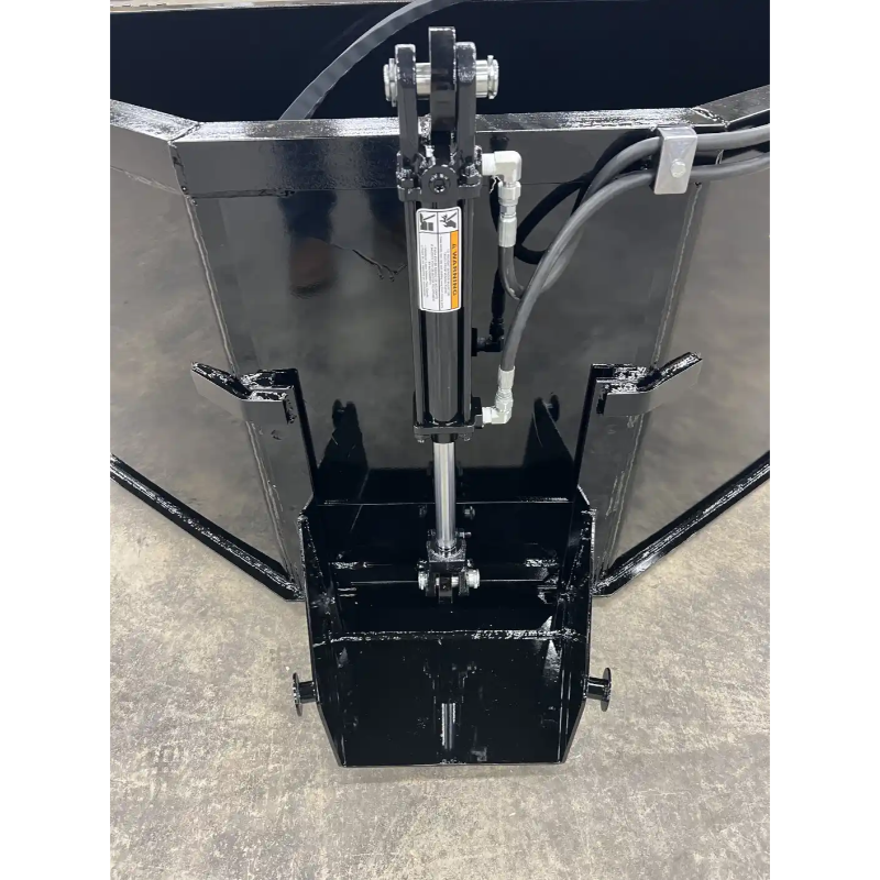 Black steel skid steer concrete bucket with central hydraulic cylinder and welded mounting brackets on concrete floor