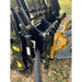 Close-up of black steel clam grapple attachment with hydraulic hoses and yellow skid steer mounting bracket outdoors on dirt and leaves