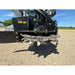 Skid steer stump grinder attachment with steel cutting wheel, multiple teeth, hydraulic motor, and black mounting frame on gravel surface