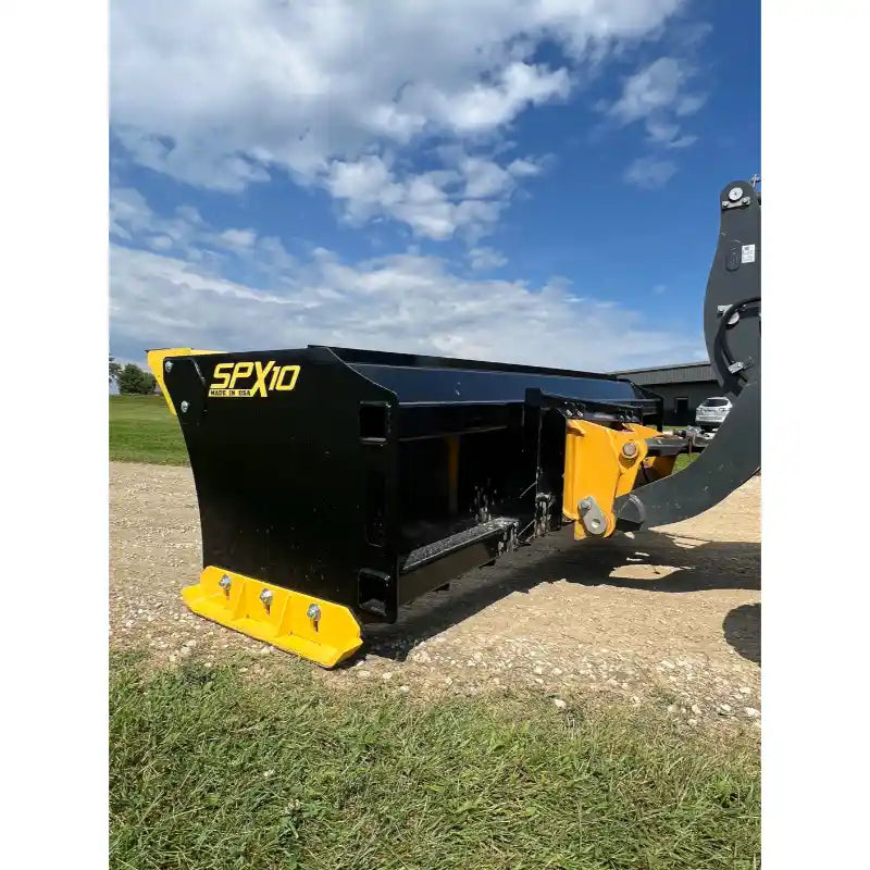Black steel skid steer snow pusher attachment with yellow bolt-on cutting edge on gravel and grass under cloudy sky
