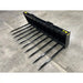Front-left view of black steel manure spear attachment with ten long pointed tines on concrete floor