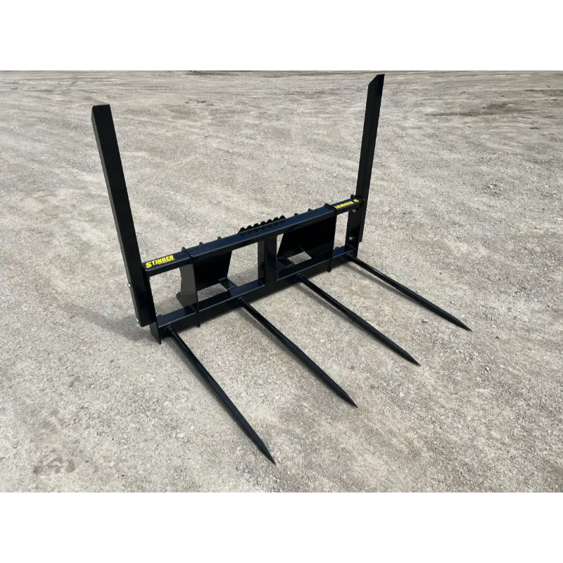 Black steel hay spear attachment with five long spikes on gravel surface outdoors