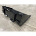 Rear angled view of black steel skid steer material bucket with reinforced mounting brackets on concrete floor