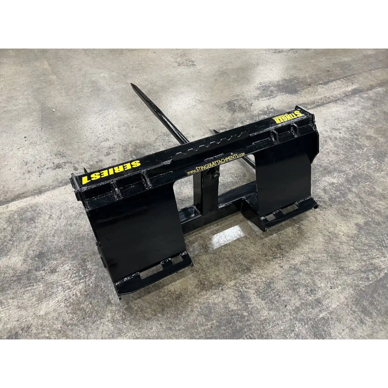 black skid steer attachment with pointed spike on top and yellow "STINGRAY" branding on concrete floor